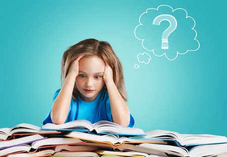 Little girl writing something in copybook and sitting at tableの写真素材