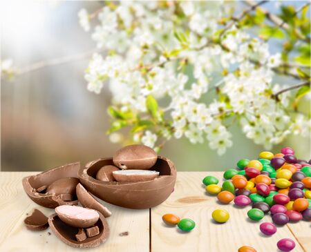 Easter composition with chocolate eggs on color wooden background, space for text