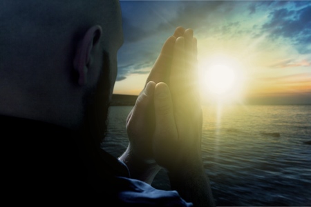 Prayer. Silhouette man prays at sunset.の写真素材