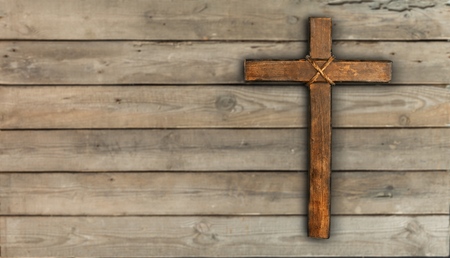 Rugged wood cross with rope hanging on antique rustic mint green wooden background; Christmas holiday background with painted copy spaceの写真素材