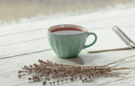 Tea cup with and tea leaf sacking on the wooden table and the tea plantations background