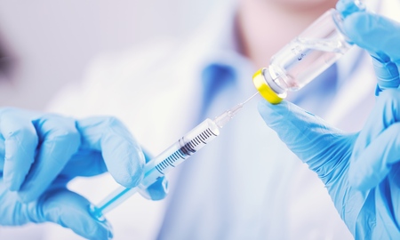 Doctor hand holds syringe and drug bottleの写真素材