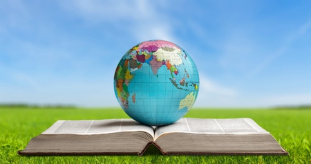 Ancient book and Earth globe with stars and universe art. Magic and space theme. Blue light on background. Planet concept. Place for text and infographic. Abstract history and astronomy theme.の写真素材