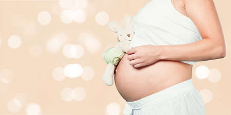 Mom in pregnancy holding a teddy bearの写真素材