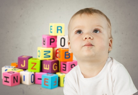 Baby in yellow shirt playing with blocks looking up surprisedの写真素材