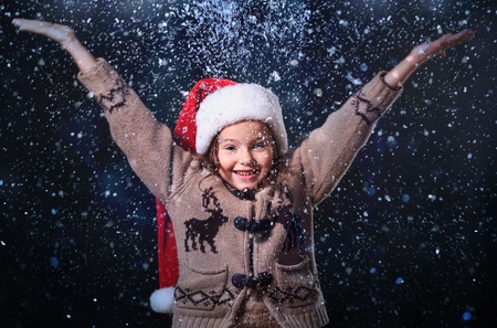 Baby playing with snow in winter. Little toddler boy in red jacket and Xmas reindeer knitted hat...