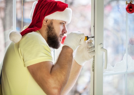 Handsome  Man in Santa's Hat repairing window for Christmas timeの写真素材