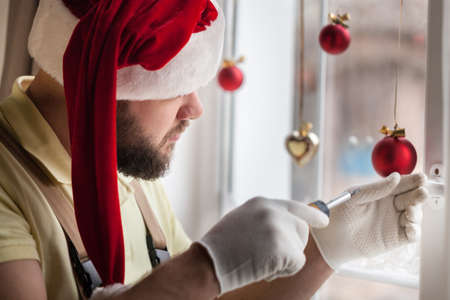 Handsome  Man in Santas Hat repairing window for Christmas timeの写真素材