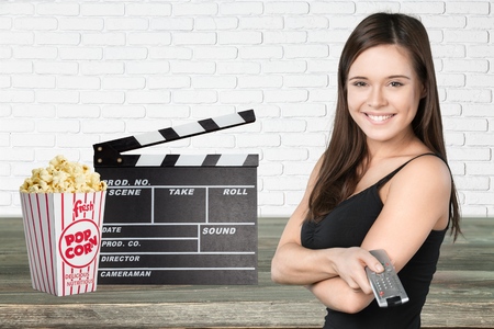 Happy woman holding TV remote control, over white background