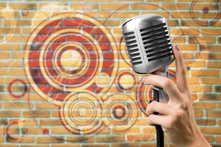 Female hand holding a single retro microphone against colourful backgroundの写真素材