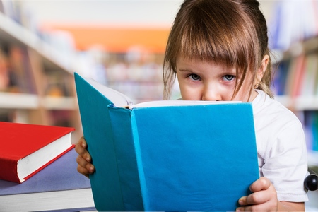 wunderkind little girl schoolgirl with a book from the blackboard with physical formulasの写真素材