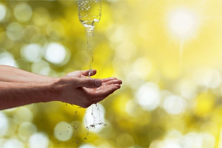 Bottled water splashing on hands.