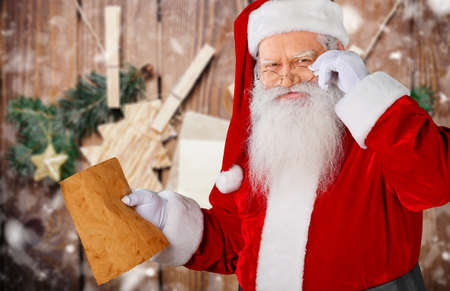 Portrait of happy Santa Claus holding Christmas letter and looking at cameraの写真素材