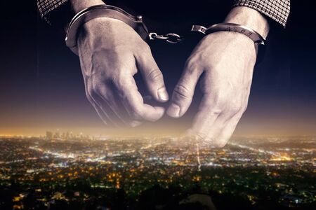 Hands of prisoner on city backgroun