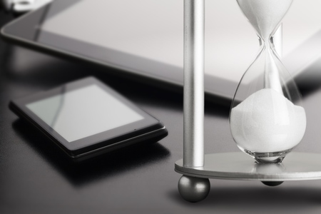 Sand running through the bulbs of an hourglass measuring the passing time in a countdown to a deadline, on a dark background with copy space.の写真素材