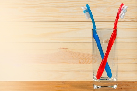 Toothbrushs in a glass on wooden tableの写真素材
