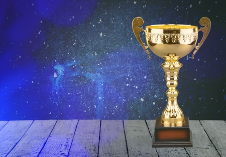 low key image of trophy over wooden table and dark background, with abstract shiny lightsの写真素材