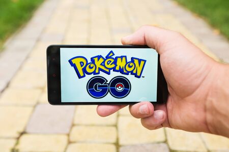 Apple iPhone5s held in one hand showing its screen with Pokemon Go application.