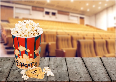Young smiling woman watching a film in the movie theater and eating popcorn, entertainment and cinema conceptの写真素材