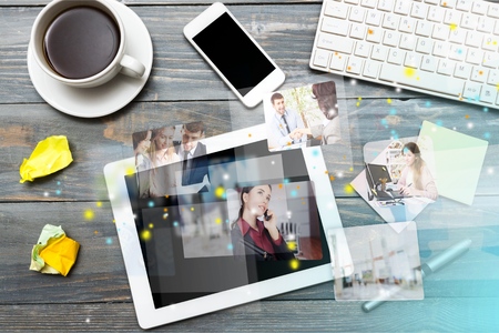 Digital tablet computer with sticky note paper and cup of coffee on old wooden desk. Simple workspace or coffee break with web surfing.の写真素材