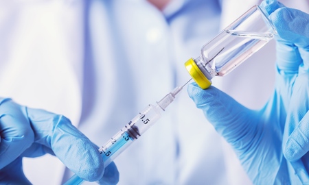 Doctor hand holds syringe and drug bottleの写真素材