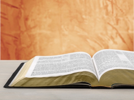 Detail of an old holy bible open with a beautiful and mystical sky in the background in a golden lightの写真素材