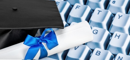 Graduation hat and diploma on laptopの写真素材