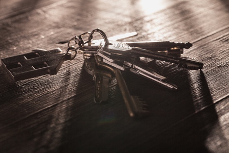 Bunch of keys with house shaped key ring on a rustic wooden tableの写真素材