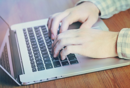 Hands typing text on a laptop keyboardの写真素材
