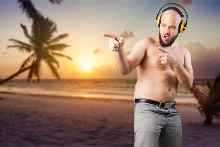 Cheerful fat man is listening to musicの写真素材