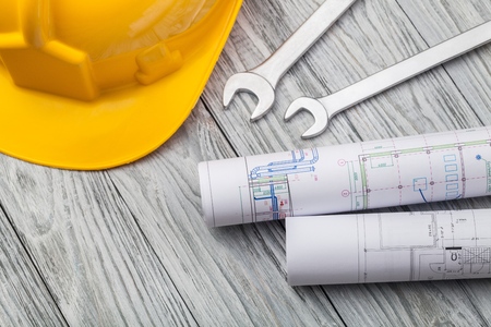 Hard hat construction plans on wooden board building concept.