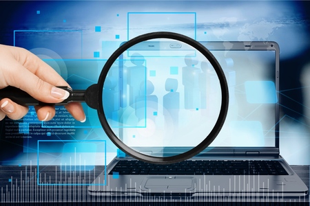 Hand holds the magnifying glass in front digital tabletの写真素材