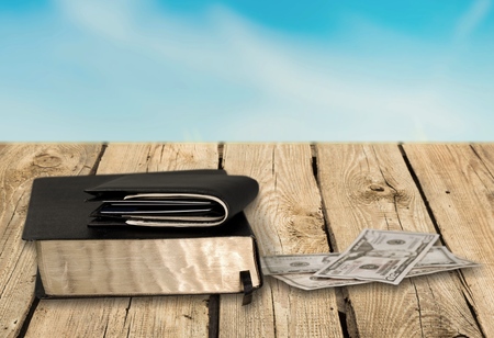 Wallet on worn black Bible with cash