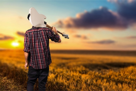 silhouette of musician with guitar at sunset field, music backgroundの写真素材