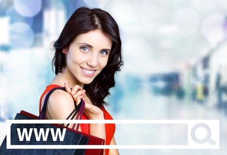 Young woman holding shopping bags and a mobile phoneの写真素材
