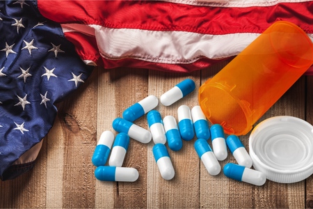 Pills spilling from prescription bottle and flag