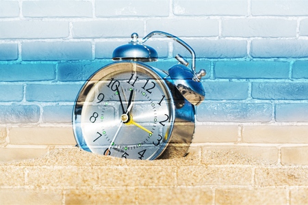 Classic analog clocks in the sand on the beach near the sea. For the holidays.