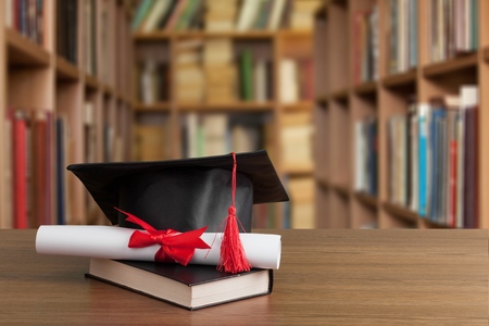 Graduation hat on stack of booksの写真素材