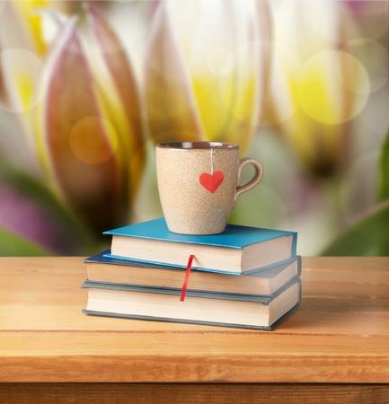 Old vintage books and cup with heart shape on wooden tableの写真素材