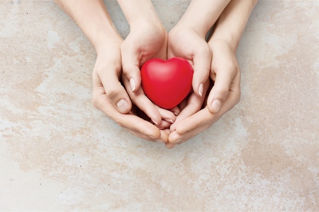 adult and child hands holding red heart