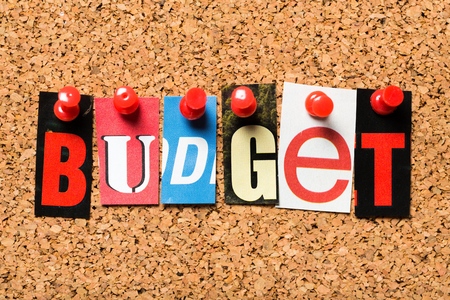 Newspaper clipping of the word Budget pinned to a cork notice board. Budget applies to balance the economy debt by government and by individuals managing their home finances.の写真素材