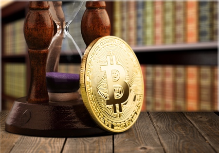 Physical bitcoin and hourglass on desk
