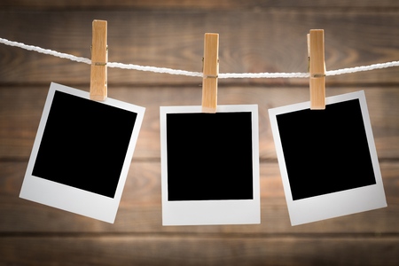 Three blank instant photos hanging on the clothesline. On old wood background.