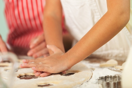 Mother and little girl making a cake together - spreading the filling