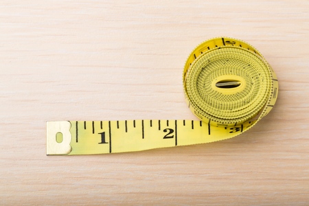 Tape measure on old wooden background. Top view.