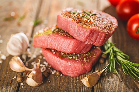 Raw beef steak on a dark wooden table.の写真素材