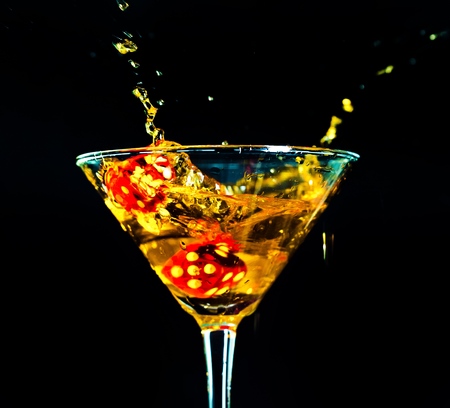 red dice falling into full cocktail glassの写真素材