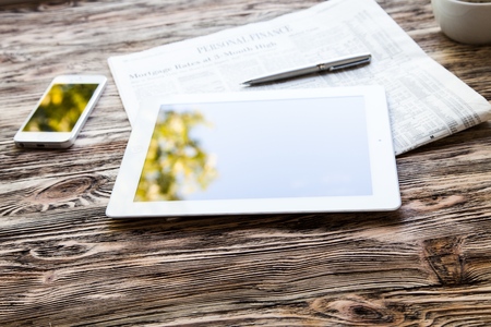 Modern workplace with digital tablet computer and mobile phone, cup of tea, pen and paper with numbers.の写真素材