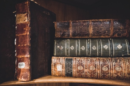 Vintage, antiquarian  books pile on wooden surface in warm directional light. Selective focusの写真素材