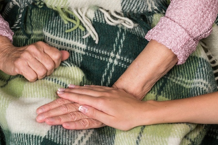 Young Woman's Hand Touching and Holding an Old Woman's Handの写真素材
